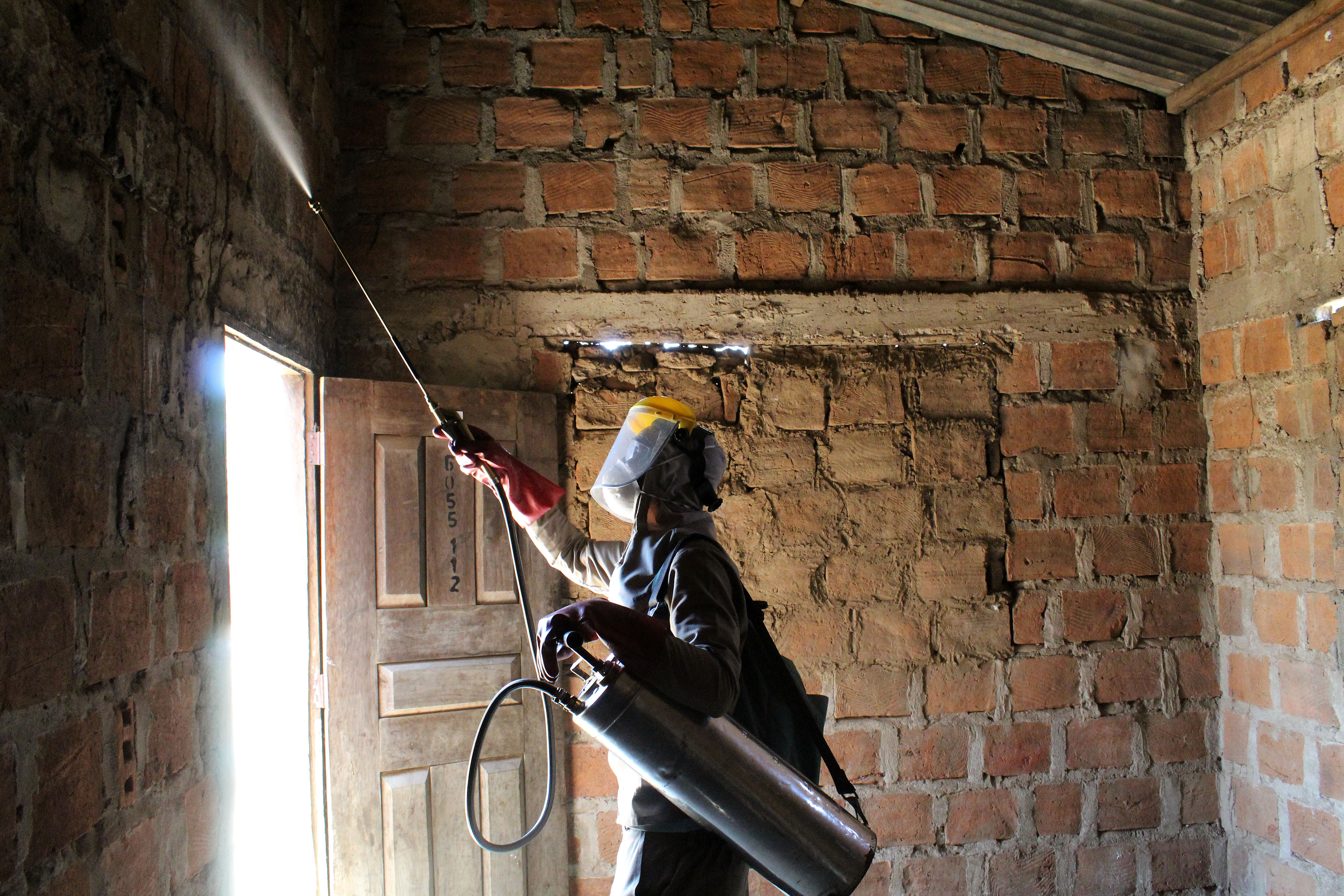 A health worker is spraying the inside walls of homes with long-lasting insecticides.